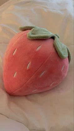 a pink strawberry pillow sitting on top of a bed