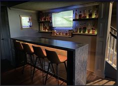 a bar with four stools in front of it and a television on the wall