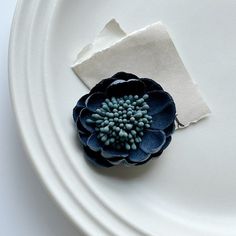 a white plate topped with a blue flower and a piece of paper on top of it