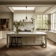 a large kitchen with white cabinets and wooden floors is pictured in this image, there are two stools at the center of the island