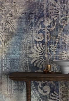 a table with two bowls on it in front of a wallpapered background that is blue and white