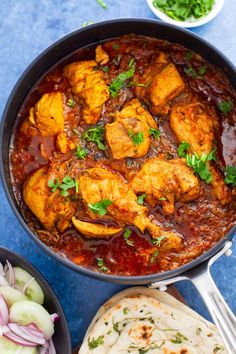 chicken curry in a skillet with pita bread and salad on the side, ready to be eaten