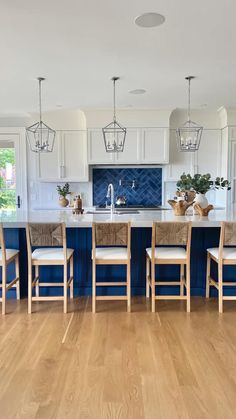 a large kitchen with blue cabinets and white counter tops, along with wooden flooring