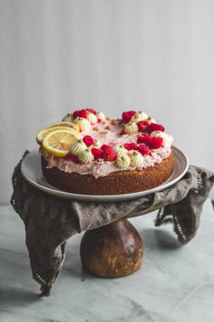 a cake sitting on top of a white plate covered in frosting and raspberries