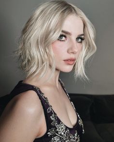 a woman with blonde hair wearing a black dress and diamond necklace, posing for the camera