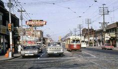 an old time photo of cars and buses on the street in front of shops, stores, and businesses