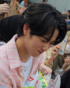 a young man holding a cell phone to his ear while wearing a pink and white shirt