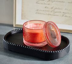 a red candle sitting on top of a black tray