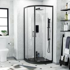 a bathroom with a stand up shower next to a white toilet and black shelving