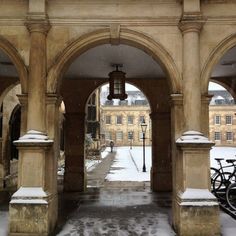 an archway with snow on the ground and bicycles parked outside