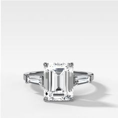 an emerald - cut diamond ring with baguets on the shoulders and side stones