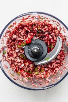 a food processor filled with red and green vegetables on top of a white countertop