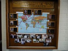 a bulletin board with pictures and photos on it in front of a wall mounted map