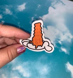 a hand holding up a sticker with an image of a dog in the sky