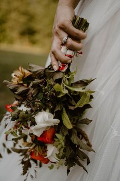 a bride holding a bouquet of flowers in her hand and wearing an engagement ring on her finger