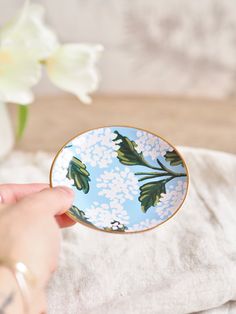 a person holding a blue and white plate with flowers on it