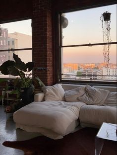 a living room filled with furniture next to a large window overlooking a cityscape