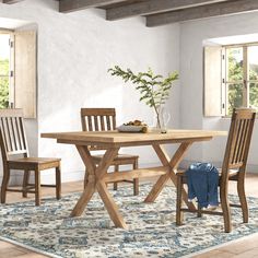 a dining room table with chairs and a rug on the floor in front of it