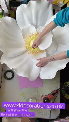 a woman is working on a large white flower