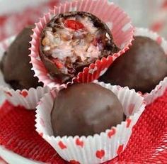 three pieces of chocolate are on a red and white plate with paper wrappers around them