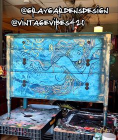 an old dresser is painted with blue and yellow designs