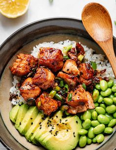 a bowl filled with rice, peas and chicken next to a wooden spoon on top of a table