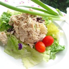 a white plate topped with lettuce, tomatoes and chicken salad next to green onions