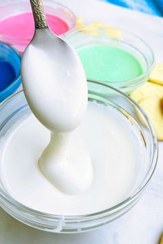 a spoon full of white liquid sitting on top of a bowl