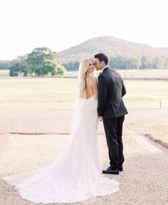 a bride and groom standing in front of a mountain