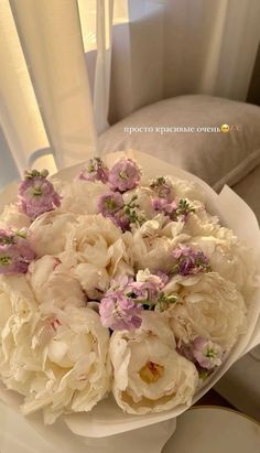 a bouquet of white and pink flowers in a bowl on a table next to a window