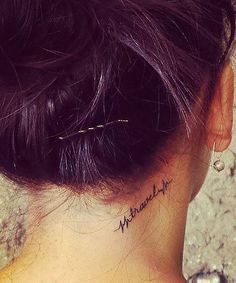 the back of a woman's neck is shown with her name tattooed on it