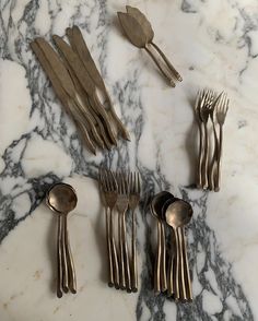 five forks, six spoons and two knives on a marble table