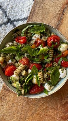 a bowl filled with pasta salad on top of a wooden cutting board