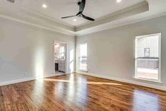 an empty room with hard wood floors and ceiling fan in the center, white walls