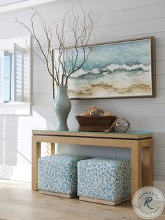 a vase filled with flowers sitting on top of a wooden table next to a painting