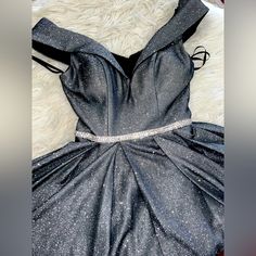 a black dress with silver glitters on it is laying on a white furnishing