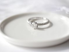 two wedding rings sitting on top of a white plate next to a silver ring holder