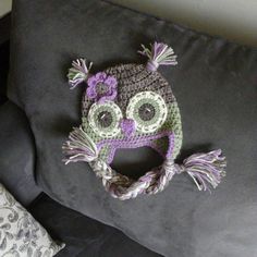 a crocheted owl hat sitting on top of a gray couch next to pillows