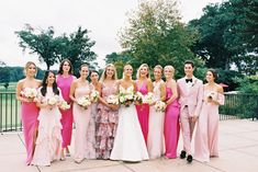 a group of women standing next to each other wearing pink dresses and holding bouquets