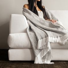 a woman sitting on a couch wrapped in a blanket