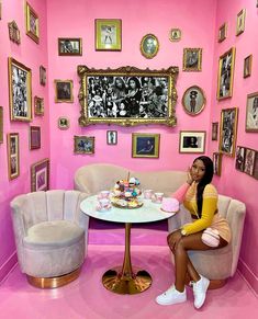 a woman sitting at a table in a pink room