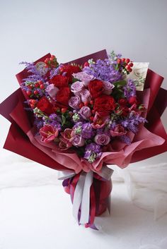 a bouquet of flowers wrapped in red and purple paper