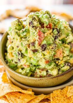 a bowl full of guacamole with tortilla chips on the side