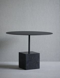 a black table sitting on top of a white floor next to a gray wall and chair