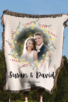 a wedding photo hanging from the side of a banner with flowers and leaves on it