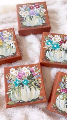 four ceramic coasters with flowers painted on them sitting on a white furnishing