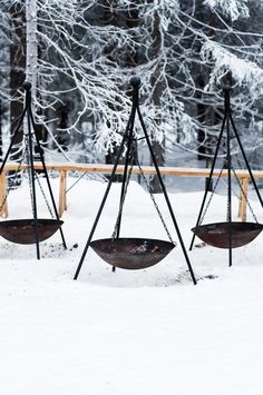 three empty swings in the snow near some trees