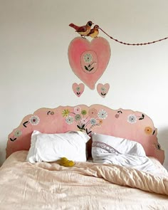 a pink headboard with hearts and flowers painted on the wall next to a bed