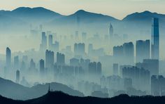 an aerial view of a city with mountains in the background and fog covering the sky