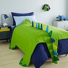 a child's bed with a green and blue dinosaur comforter on the bottom